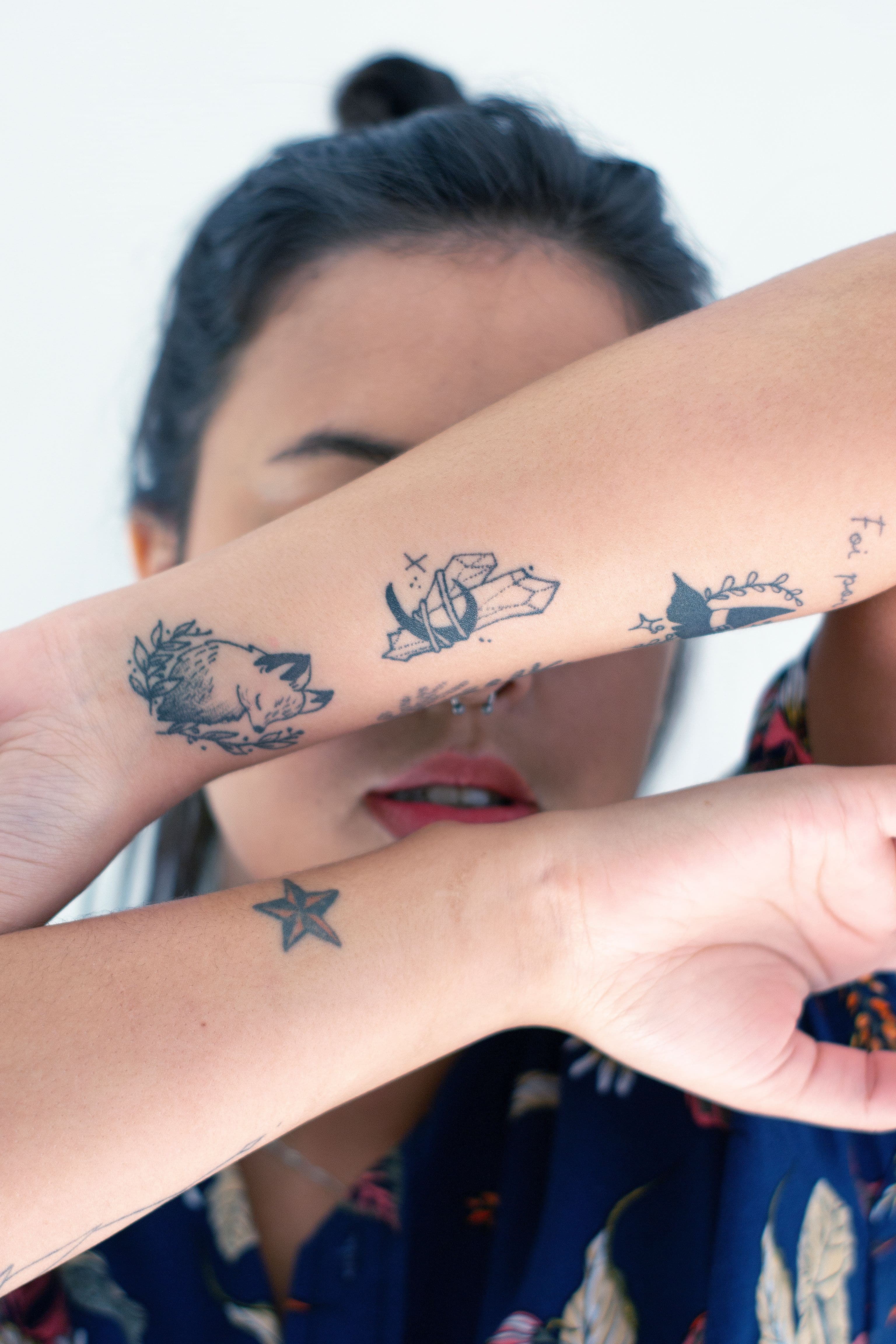 Person showing a collection of tattoos across both arms